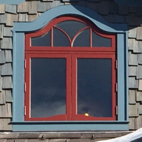 Arched window with red trim in Alpine by HS Windows.